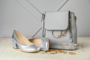 Stylish handbag with female accessories on a table